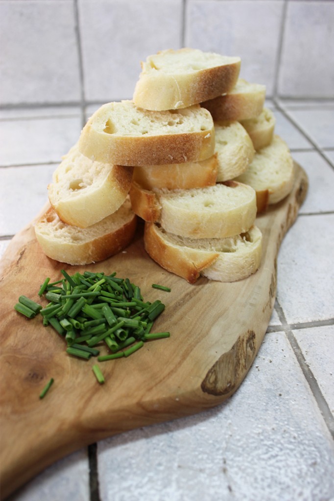 Chopped baguette and chives on a cutting board.