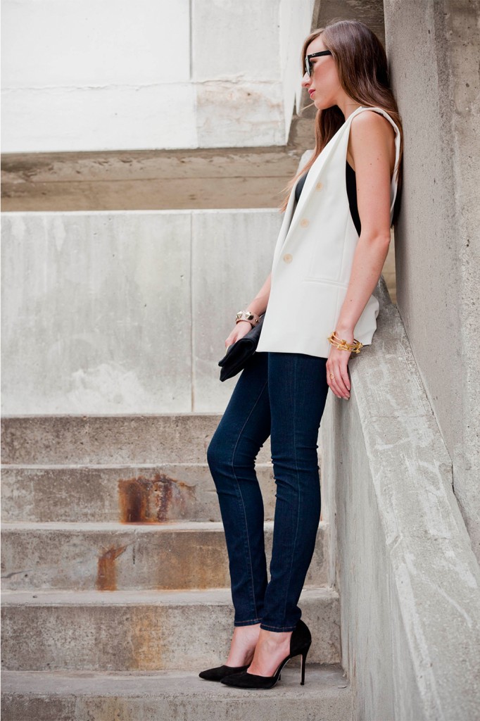 Style in white vest, jeans, black top with black clutch and heels